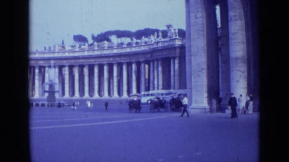 A wide Rome view from 1962 shows the St. Peter's area colonnade, open pavement, pedestrians, cars, and the edge of a large stone structure.