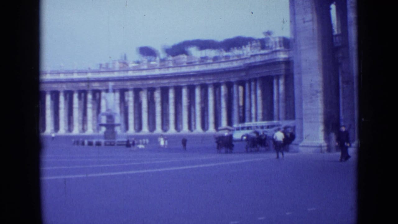 1962 Rome home-movie frame showing St. Peter's Square colonnade, a fountain, scattered pedestrians, and period cars.