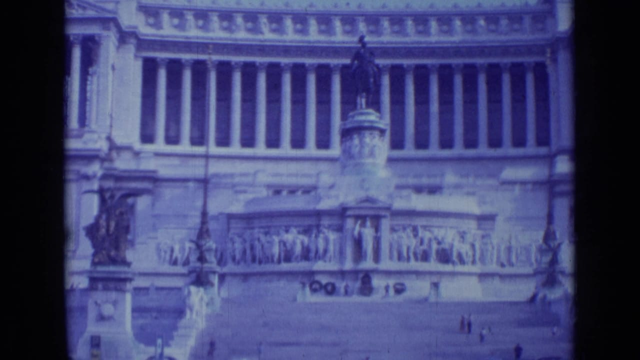 Classical facade with tall columns, sculptural relief, central steps, and a statue in front.