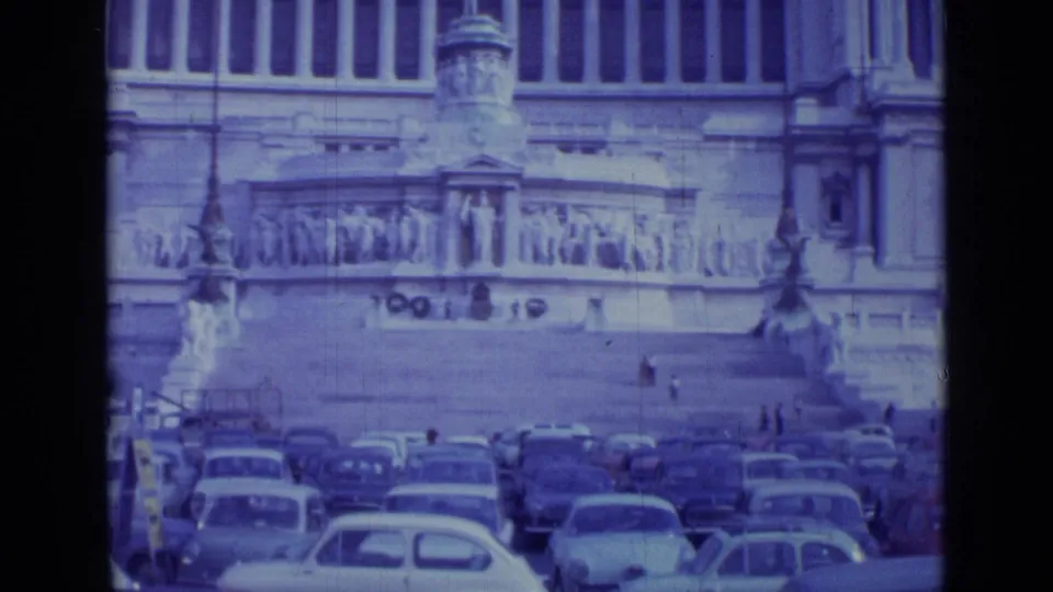 1962 Rome home-movie view of a monumental public square, with parked cars in the foreground and pedestrians on the steps.