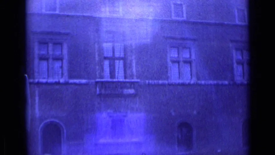 1962 Rome 8mm frame showing a city building facade with windows and arches, softened by blue color shift and bright exposure flare.