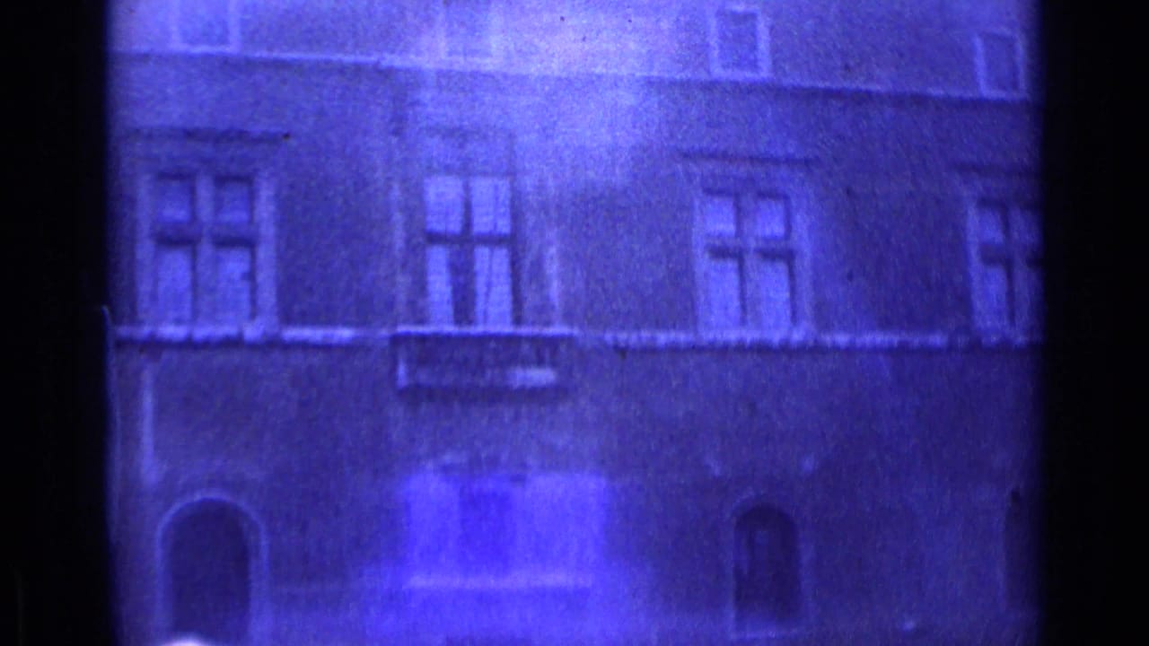 1962 Rome home-movie frame showing a soft blue-purple view of an old masonry facade with windows and arched openings.