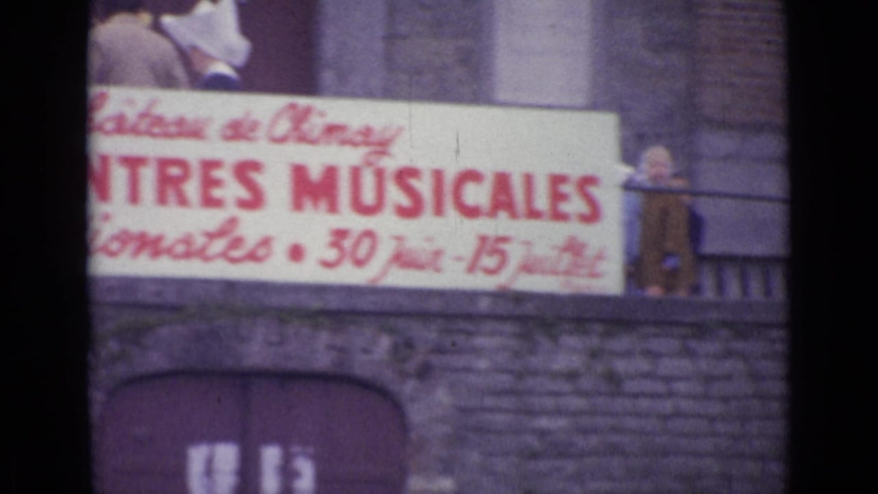 1962 8mm frame cataloged as Switzerland showing a Château de Chiny musical-event banner on a stone facade with an adult above it.