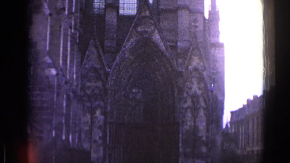 1962 Switzerland 8mm frame showing a shadowed Gothic-style stone facade, possibly a church, filmed from street level.