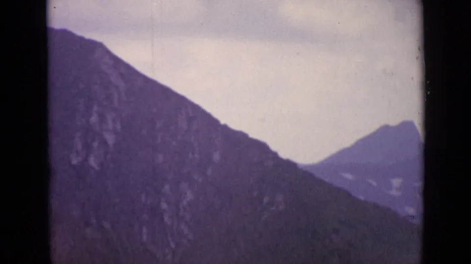 1962 Switzerland 8mm view of a rocky alpine slope crossing the frame with a distant peak beyond it.