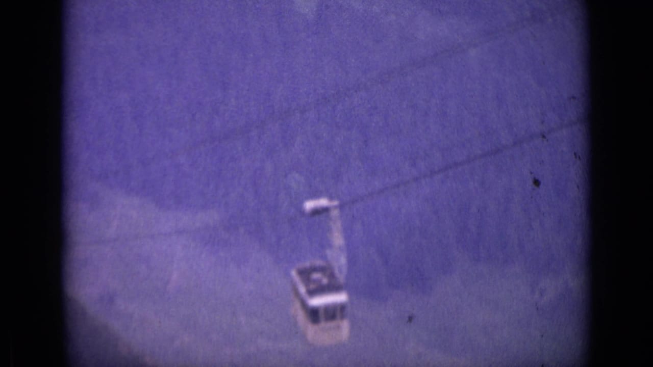 Small cable car on a line against a hazy purple mountain sky.