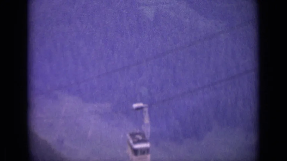 The cable car appears farther along the overhead line, seen through soft 1960s Swiss home-movie footage.