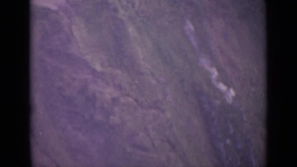 1962 Swiss 8mm frame showing a blurred grassy mountainside and rugged terrain from a high, handheld viewpoint.