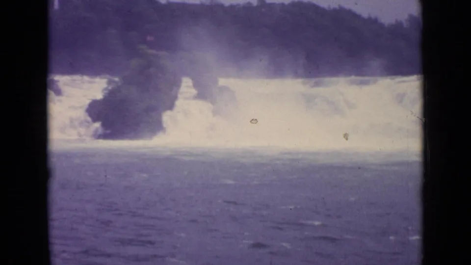 8mm footage from Switzerland in 1962 showing overexposed white rapids, mist, and a dark wooded rock mass in the current.