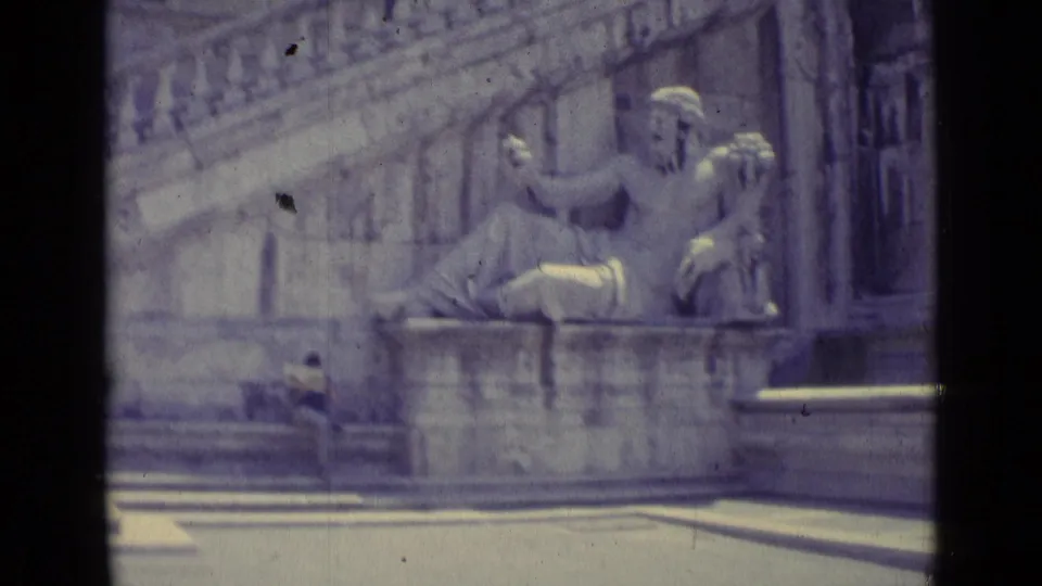 1962 Vatican City home-movie view of the seated classical statue on a pedestal against a large stone architectural backdrop.