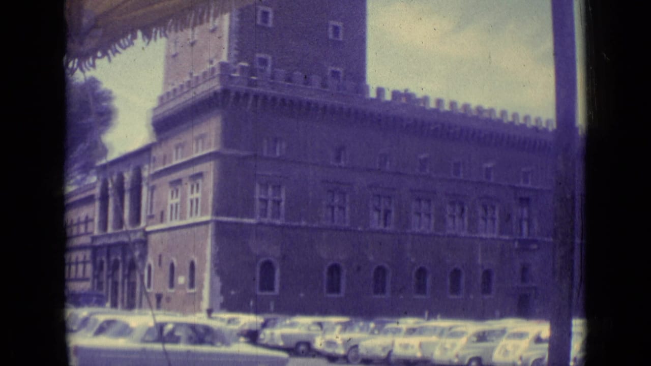 Crenellated historic building behind a row of parked cars.