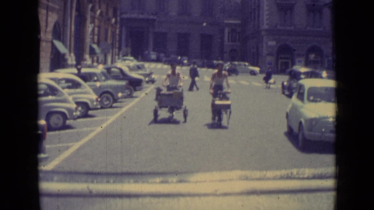Small carts travel away from the camera between parked cars and pedestrians.