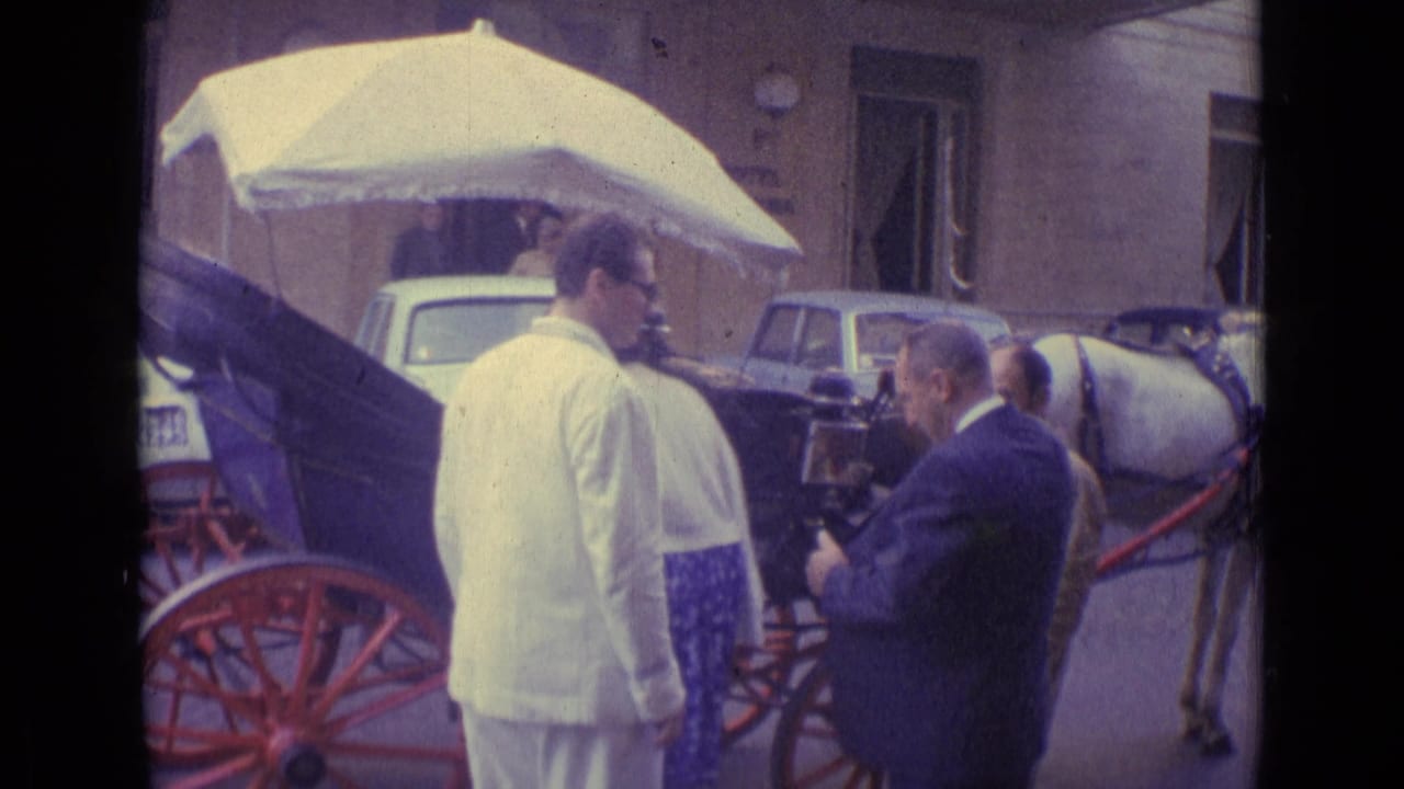 1962 Vatican City home-movie frame showing men talking near a carriage with red wheels and a woman seated beneath a white umbrella.