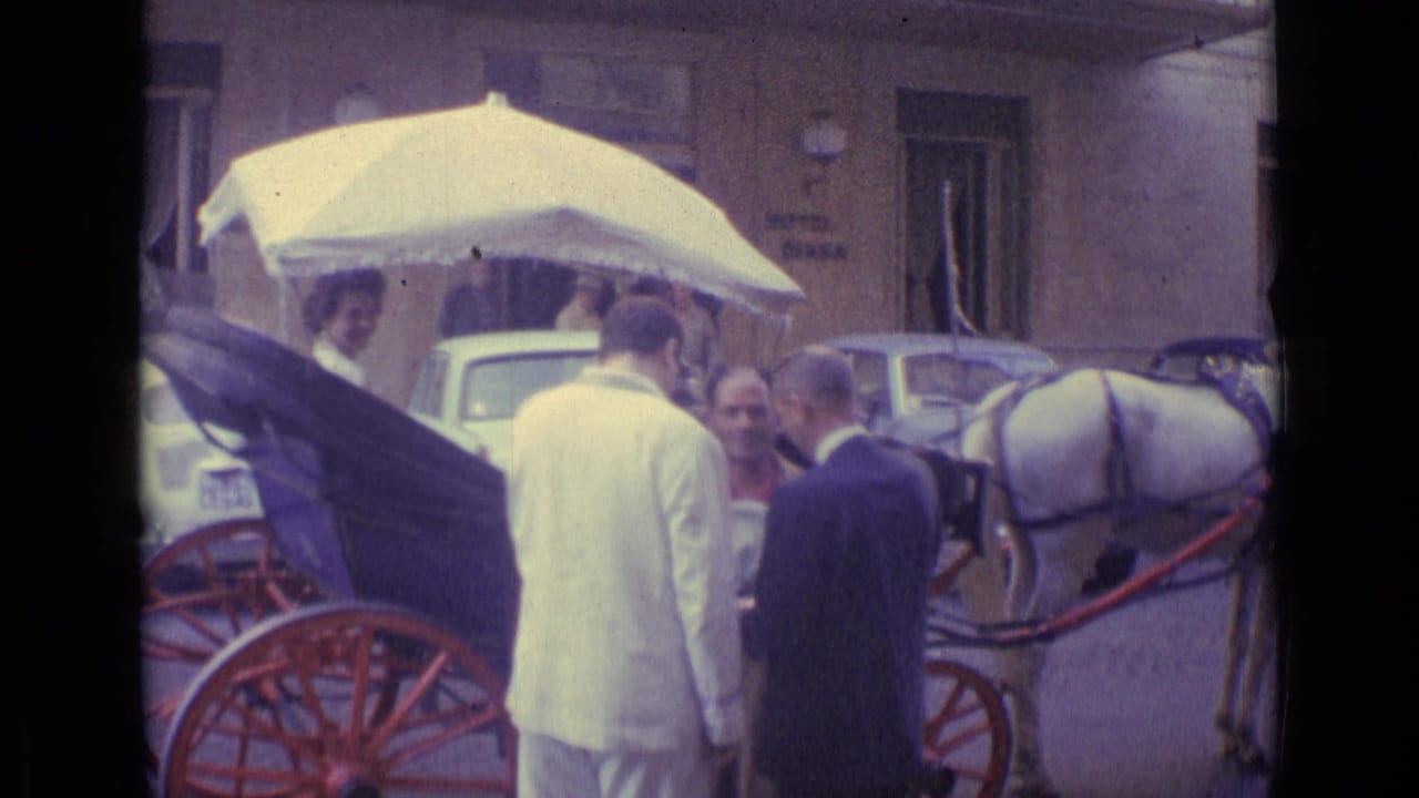 1962 Vatican City home-movie frame showing adults around a horse-drawn carriage near parked cars and a Hotel Diana sign.