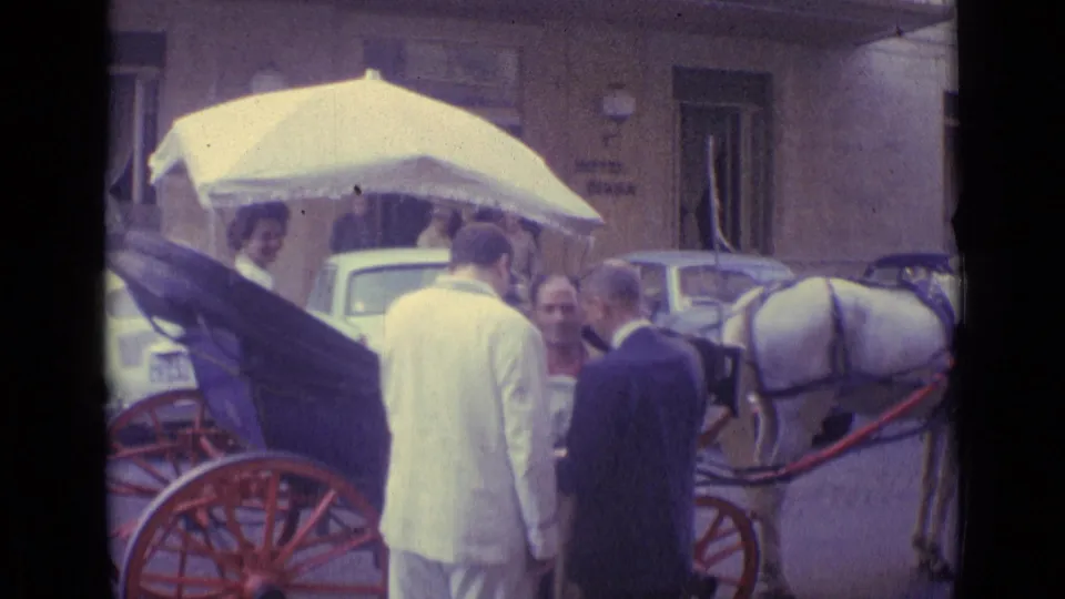 1962 Vatican City home-movie frame showing adults around a horse-drawn carriage near parked cars and a Hotel Diana sign.