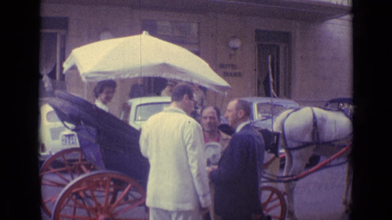 1962 Vatican City street frame with adults beside a horse-drawn carriage, a seated woman, red wheels, and hotel signage.