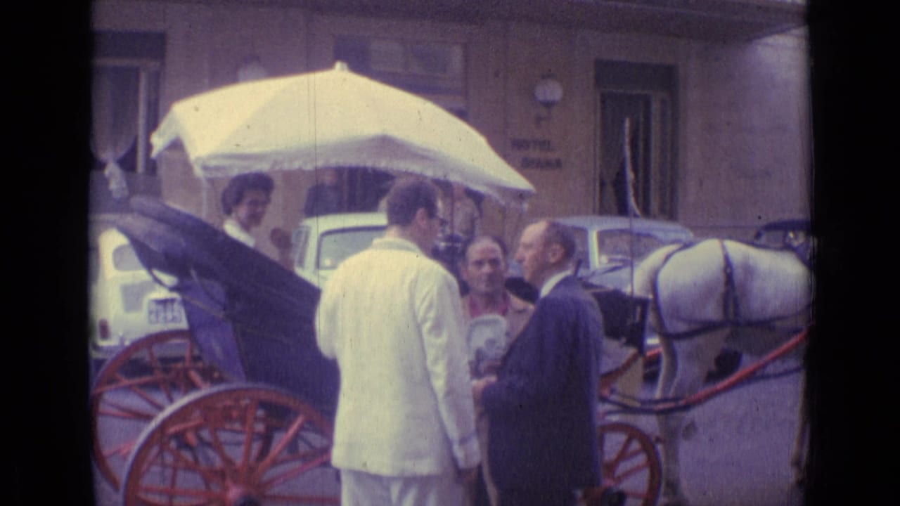 1962 Vatican City street view with adults near a horse-drawn carriage, parked cars, and building fronts in soft 8mm color.