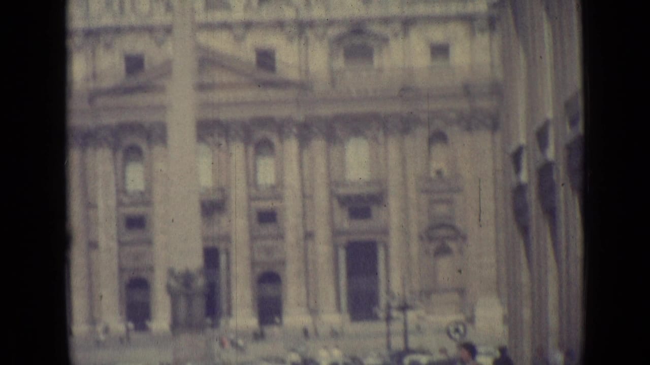1962 Vatican City frame showing St. Peter's Basilica facade, dome and obelisk through a softly focused 8mm travel-film view.