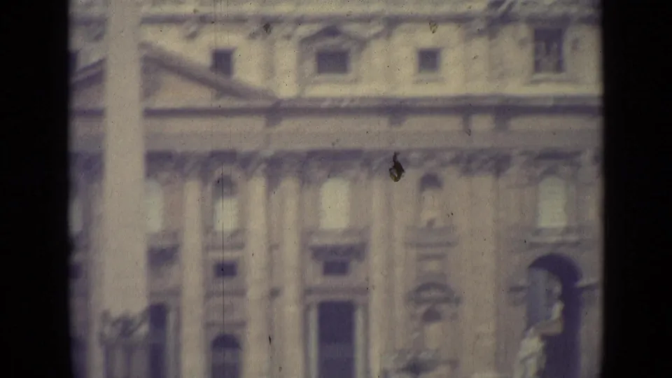 1962 Vatican City 8mm frame showing a blurred monumental facade, columns, windows, and a dark film-frame divider.