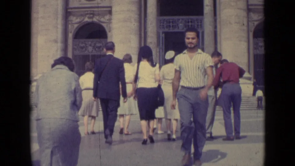 1962 Vatican City frame with pedestrians near a stone entrance and a striped-shirt man looking toward the camera.