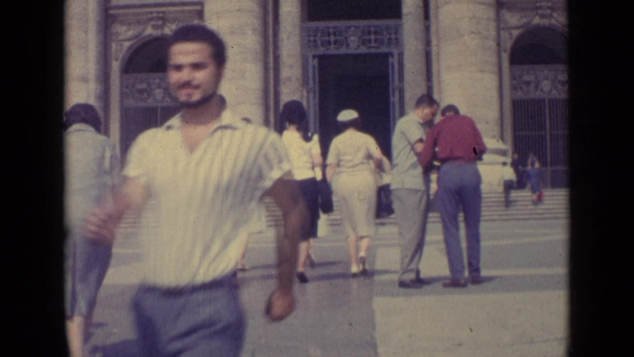 1962 Vatican City home-movie frame with a man blurred in the foreground and visitors entering near carved stone arches.