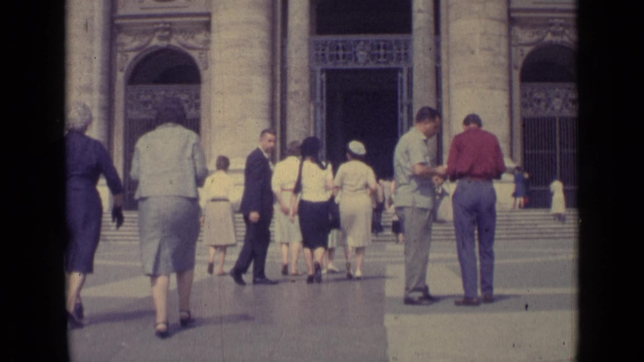 1962 Vatican City home-movie frame showing tourists in mid-century dress approaching broad stone steps and large columns.