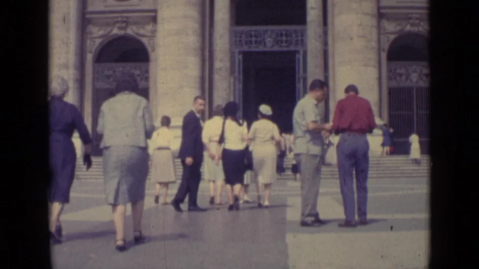 1962 Vatican City home-movie frame showing tourists in mid-century dress approaching broad stone steps and large columns.