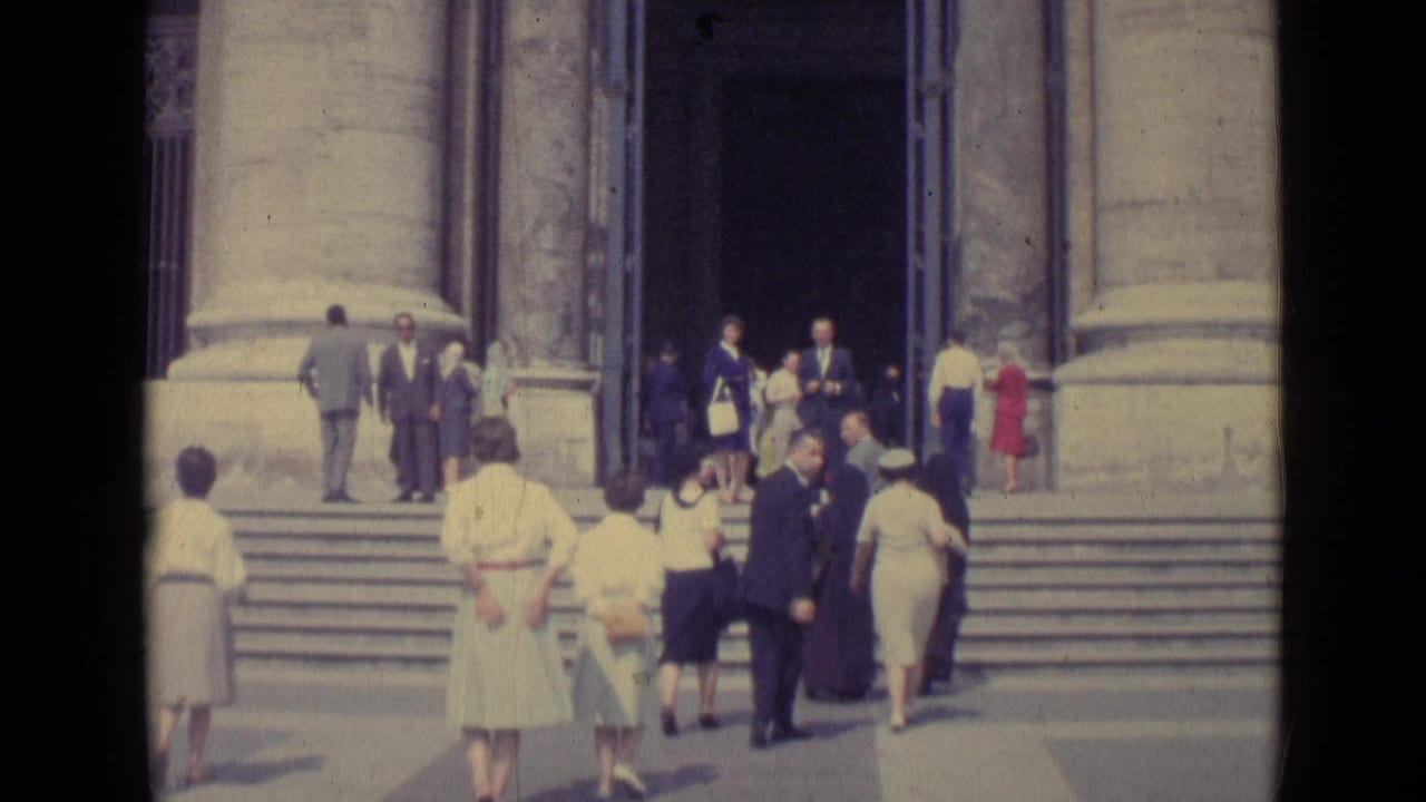 Home-movie view of Vatican City visitors on broad steps, with stone pillars and the basilica doorway in view.