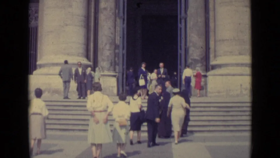 Home-movie view of Vatican City visitors on broad steps, with stone pillars and the basilica doorway in view.