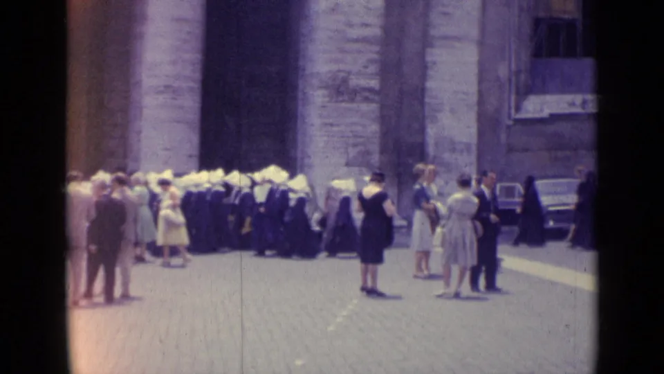 1962 Vatican City home-movie view of nuns, visitors, and pedestrians near parked cars and stone architecture.