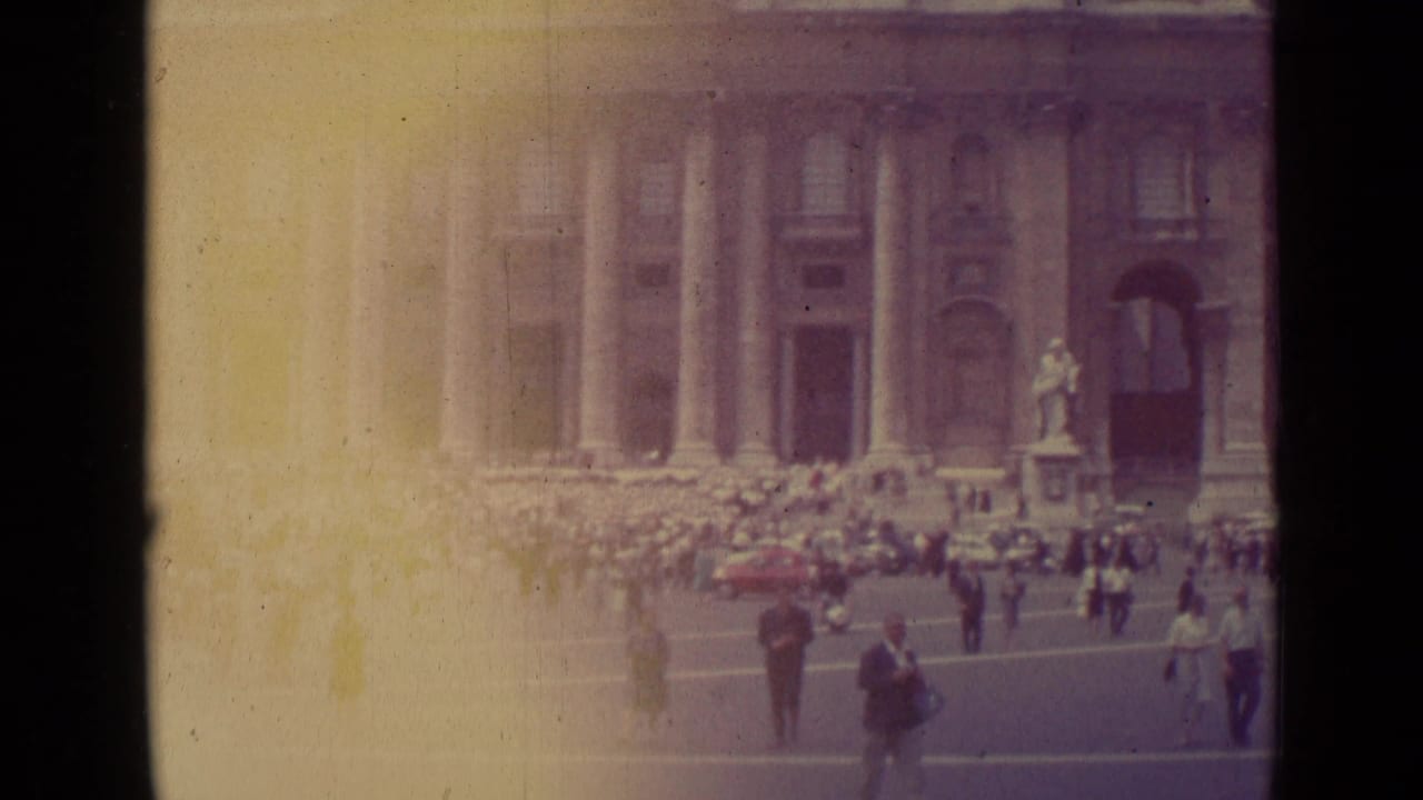 Wide view of crowds in front of St. Peter's Basilica with pedestrians in the foreground.