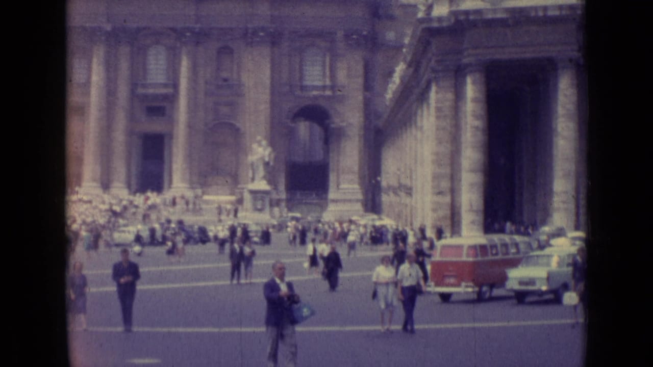 1962 Vatican City frame with pedestrians, a red-and-white van, a light-colored car, and St. Peter's Basilica in the background.