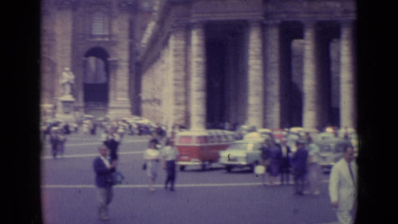 Colonnaded square with pedestrians, cars, and a red-and-white van in the background.
