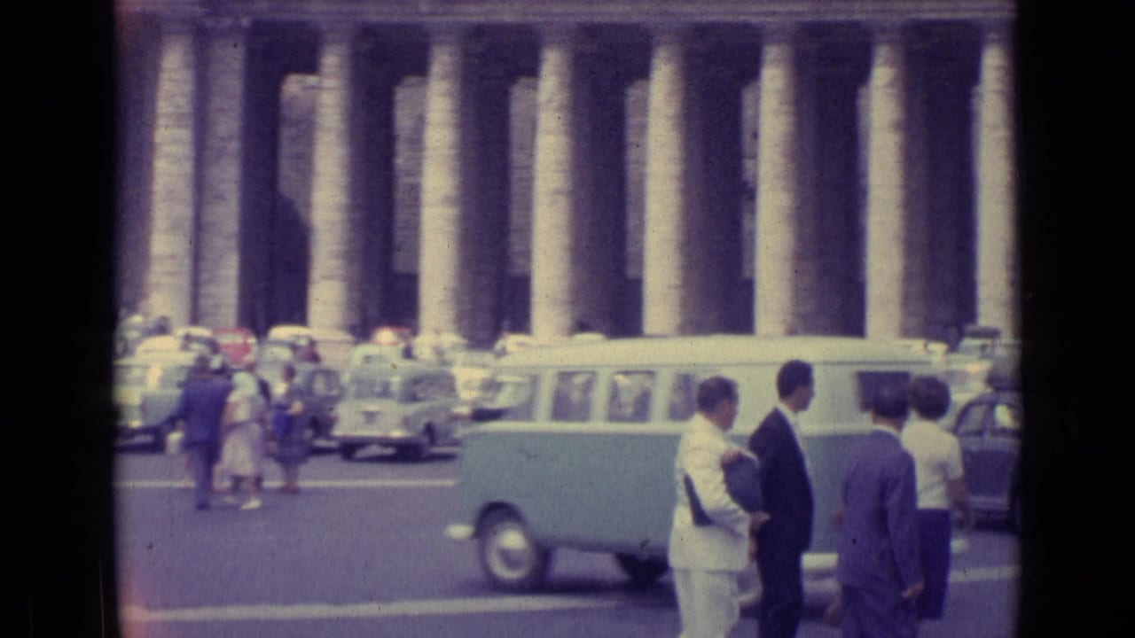 1962 Vatican City view of visitors near a pale car, with colonnade columns and parked vehicles across the square.