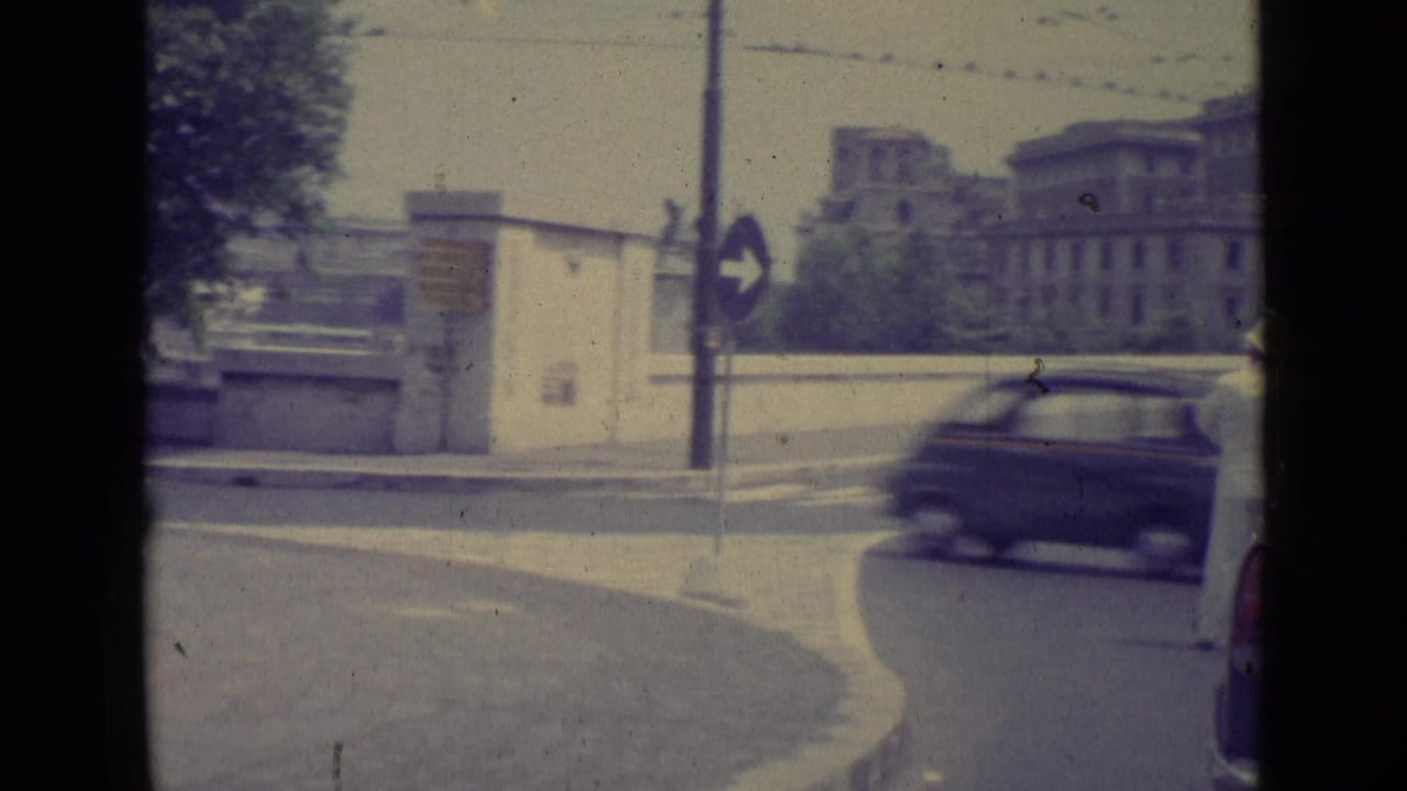 1962 Vatican City street view showing a vintage car crossing a roundabout near directional signage and monumental buildings.