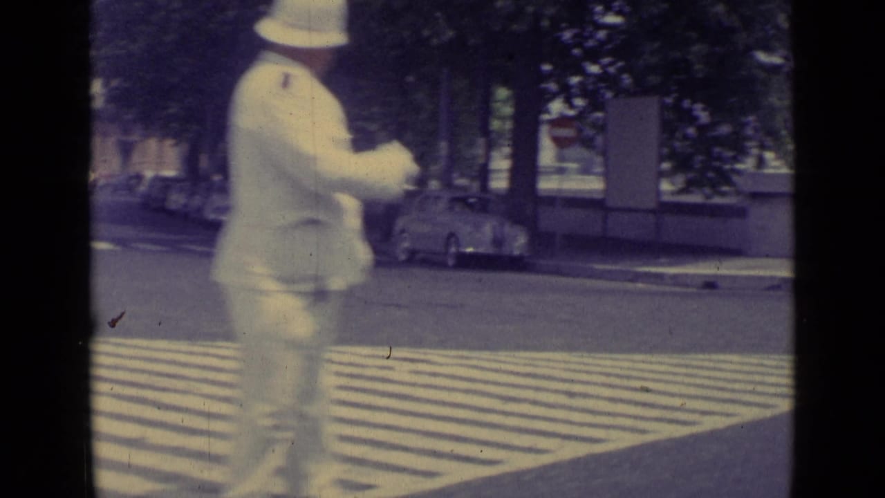 1962 Vatican City crosswalk scene with a white-uniformed traffic policeman directing street traffic near parked or passing cars.