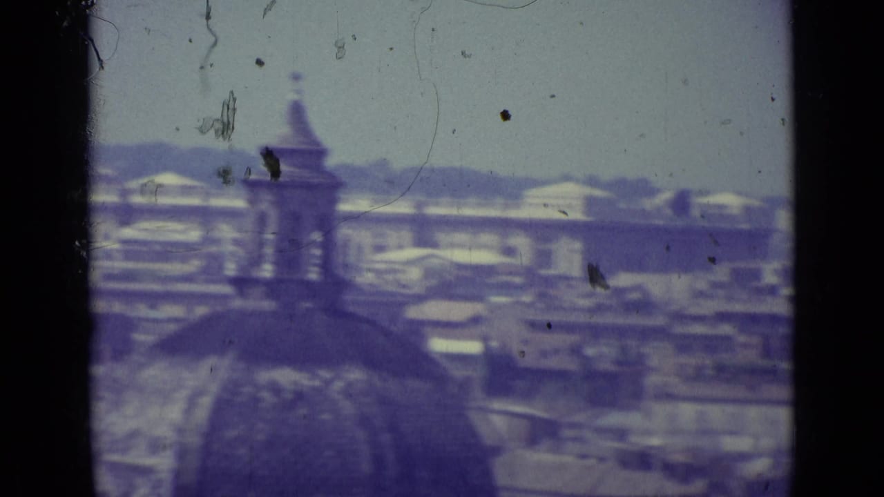 1962 Vatican City roofscape with a large foreground dome shape, spire, hazy skyline, and blue-purple film cast.