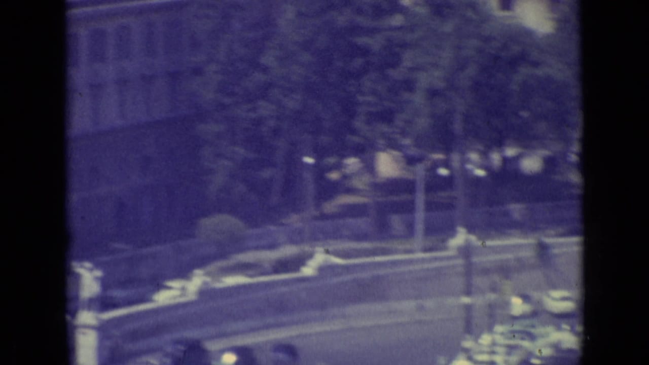 Vatican City 8mm frame with cars moving or parked along a curved road, seen through dark vertical framing.