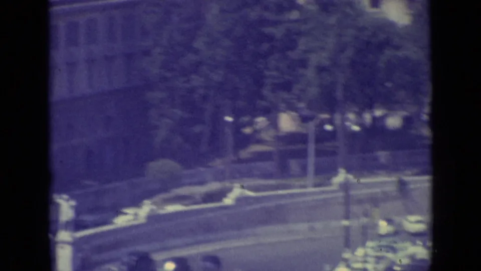Vatican City 8mm frame with cars moving or parked along a curved road, seen through dark vertical framing.