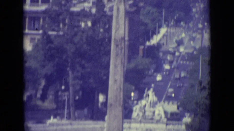 1962 Vatican City close view of a tall obelisk-like monument, trees, and soft urban detail in faded 8mm color.