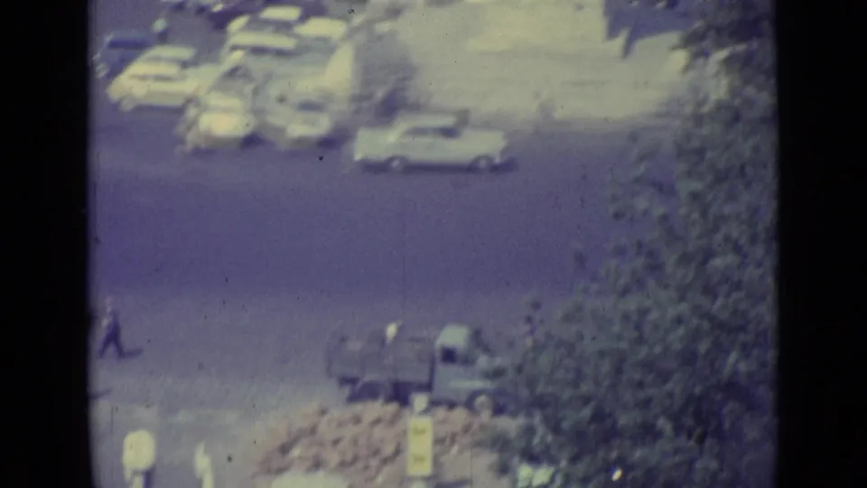 1962 Vatican City frame with cars, a small truck, pedestrians, and trees seen from above through a dark foreground edge.