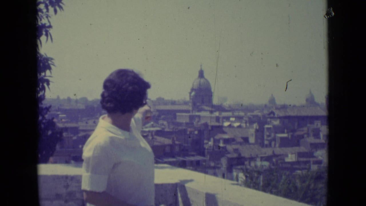 Woman faces the skyline with a domed church and rooftops in the distance.