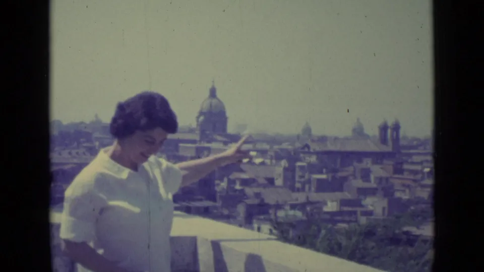 In the final frame, the woman gestures broadly on a Vatican City terrace with the domed church and city rooftops in the background.