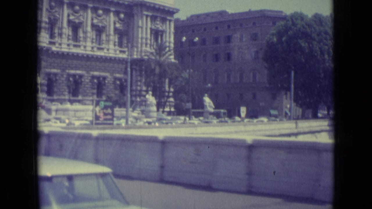 1962 Vatican City travel footage showing a formal stone building, public trees, a roadside wall, and part of a passing car.
