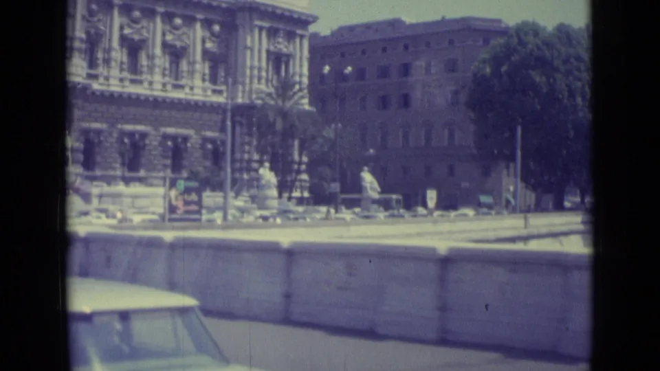 1962 Vatican City travel footage showing a formal stone building, public trees, a roadside wall, and part of a passing car.