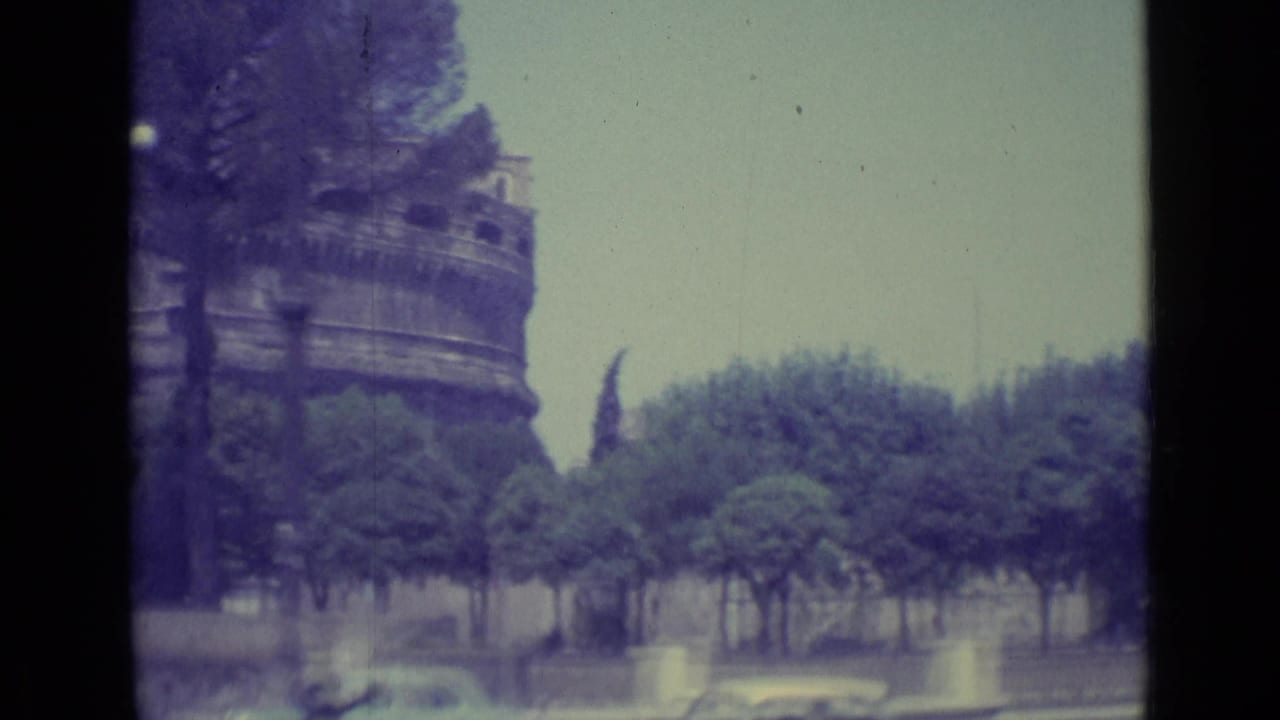 1962 8mm view near Vatican City with Castel Sant'Angelo rising behind umbrella pines and a street in the foreground.
