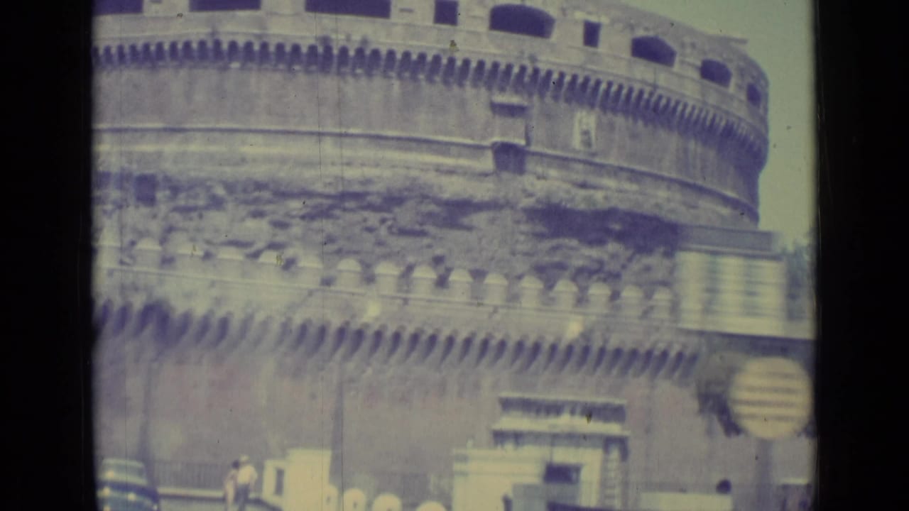 Castel Sant'Angelo wall with battlements, doorway, small pedestrians, and cars at street level.