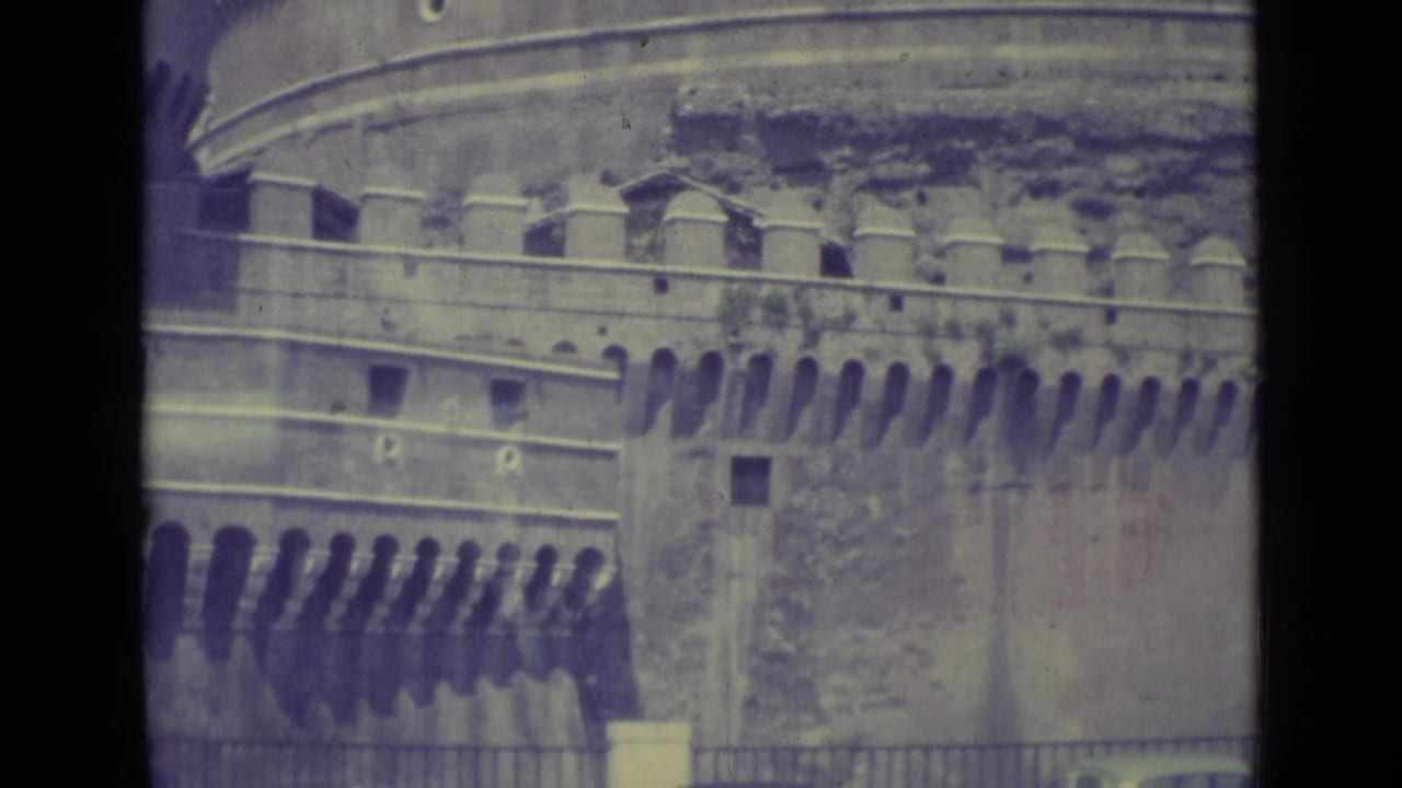 1962 8mm view of Vatican City stone walls near the Vatican Museums entrance, with crenellations and dark film borders visible.
