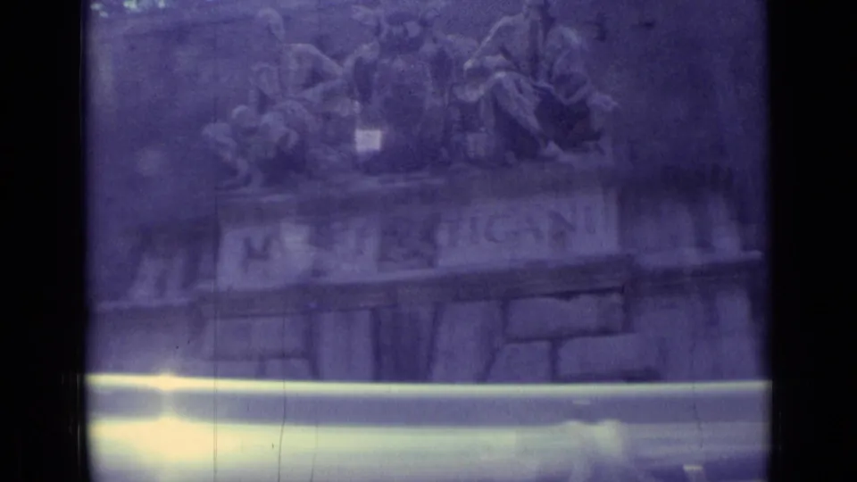 1962 8mm Vatican City footage showing the MUSEI VATICANI stone sign beneath sculpture, partly obscured by exposure flare.