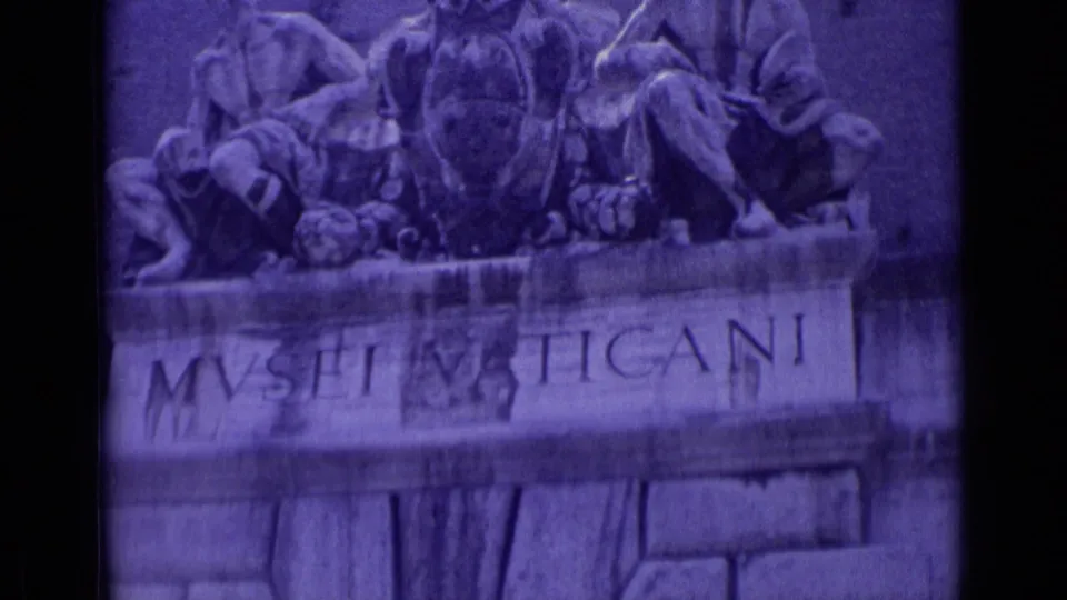 1962 Vatican City frame showing the Vatican Museums entrance sign and relief sculpture in purple-tinted 8mm footage.